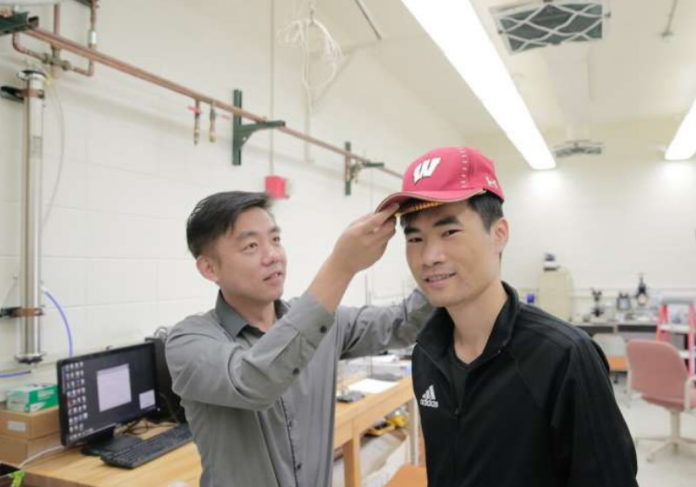 Professor Xudong Wang, especialista em engenharia de materiais da UW-Madison, testa boné em usuário. Foto: UWM
